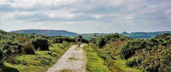 A lone Cyclist on a track surrounded by moorland with distant views