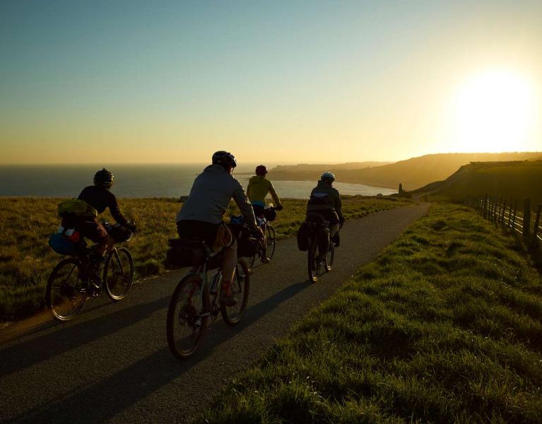 Cyclists riding towards the sunrise with the port of Dover in the distance