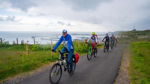Cyclists riding along a path with the port of Dover in the background.