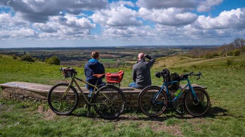 Cyclists sitting on a bench looking at a distant view of the countryside