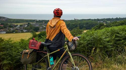 A cyclist standing next to his bike looking at sea views