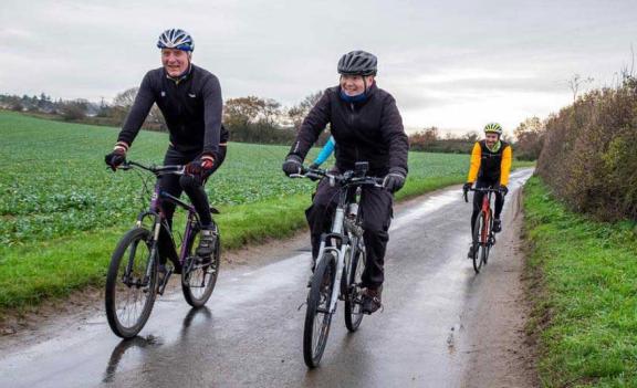 Cyclists riding along a road in the Norfolk countryside