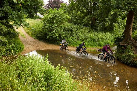 Cyclists riding through a ford in the countryside